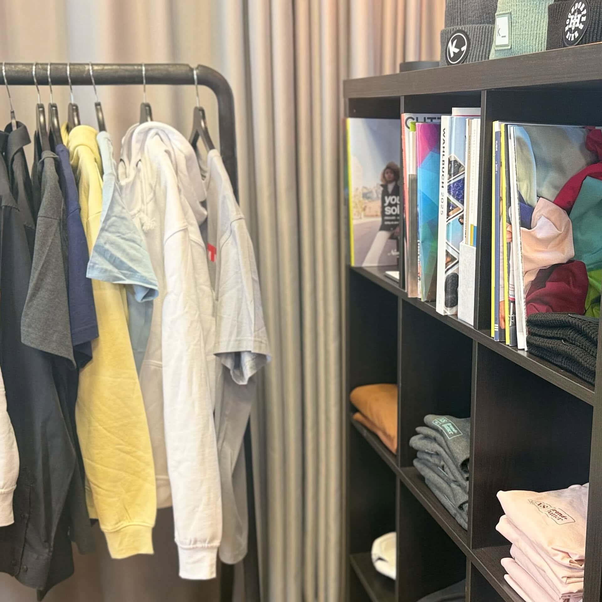 Kleiderständer mit T-Shirts und Regal mit Kleidung.